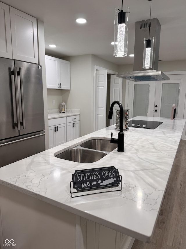 kitchen with a sink, high quality fridge, white cabinets, black electric cooktop, and extractor fan