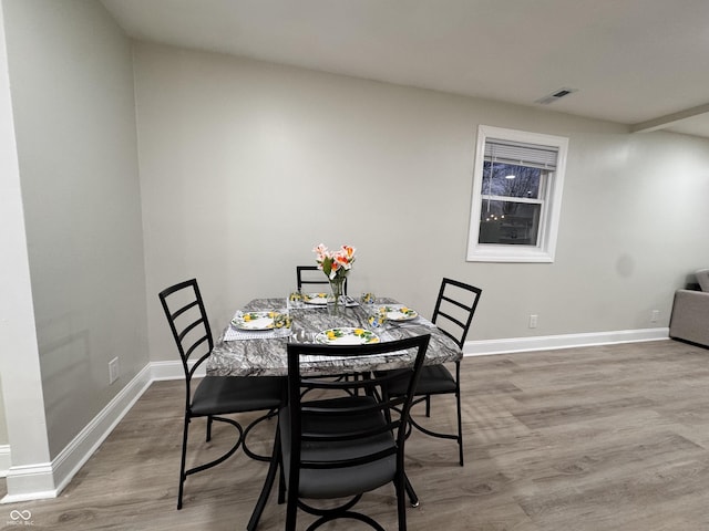 dining room featuring wood finished floors, visible vents, and baseboards