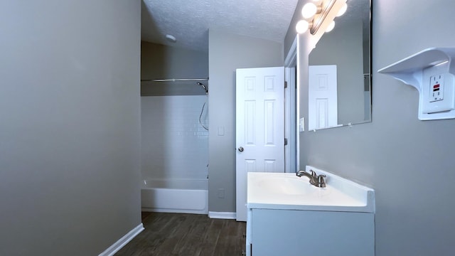 full bath with baseboards, vanity, wood finished floors, a textured ceiling, and  shower combination