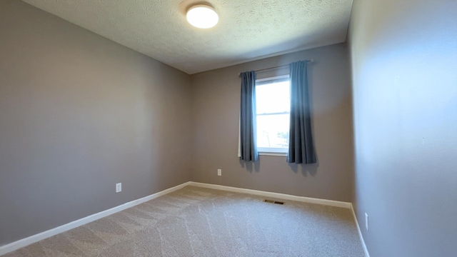 empty room with visible vents, baseboards, a textured ceiling, and light carpet