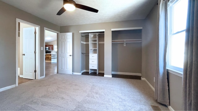 unfurnished bedroom featuring baseboards, multiple closets, and carpet