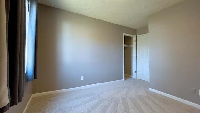 unfurnished bedroom featuring a textured ceiling, baseboards, and carpet