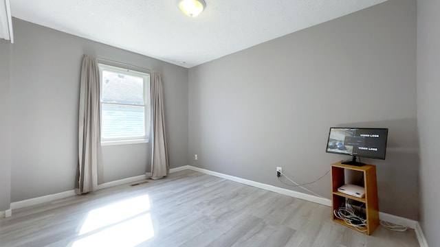 spare room with visible vents, light wood-style floors, and baseboards