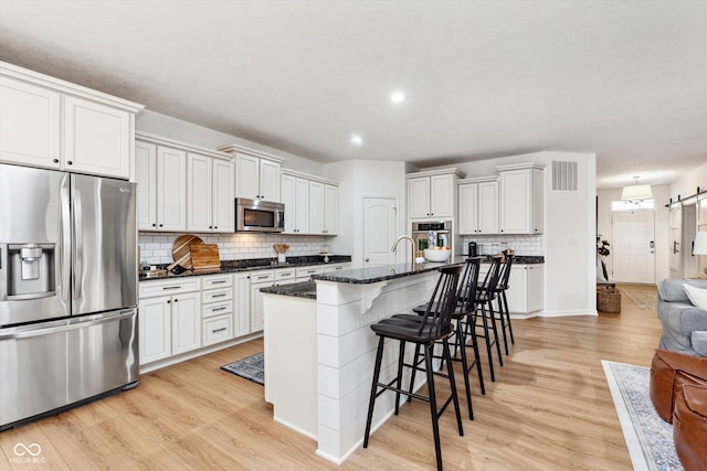 kitchen with light wood finished floors, visible vents, appliances with stainless steel finishes, and a barn door