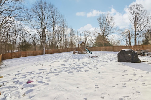 yard layered in snow with a fenced backyard and a playground