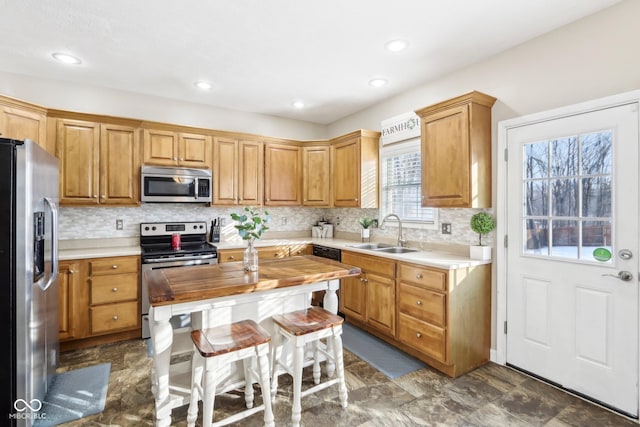 kitchen with a sink, backsplash, recessed lighting, stainless steel appliances, and butcher block counters