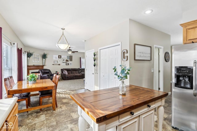 kitchen with wooden counters, ceiling fan, stainless steel fridge with ice dispenser, open floor plan, and hanging light fixtures