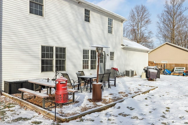 snow covered property featuring central air condition unit and fence