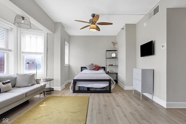 bedroom with light wood finished floors, visible vents, and baseboards