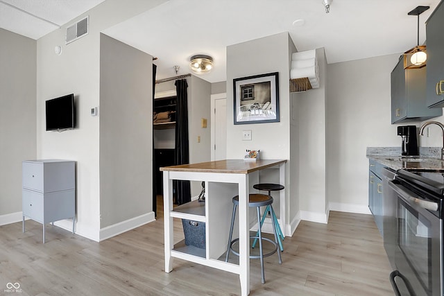 kitchen featuring baseboards, visible vents, light wood finished floors, and range with electric cooktop