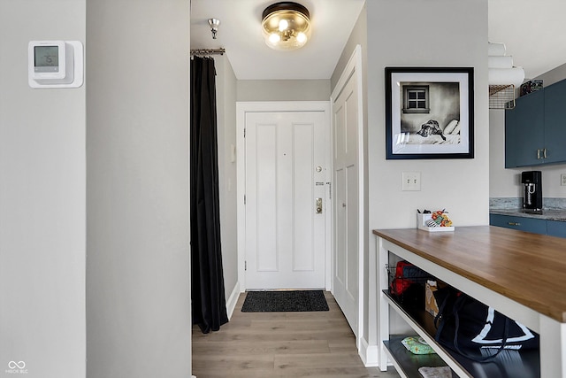 doorway with baseboards and light wood-style floors