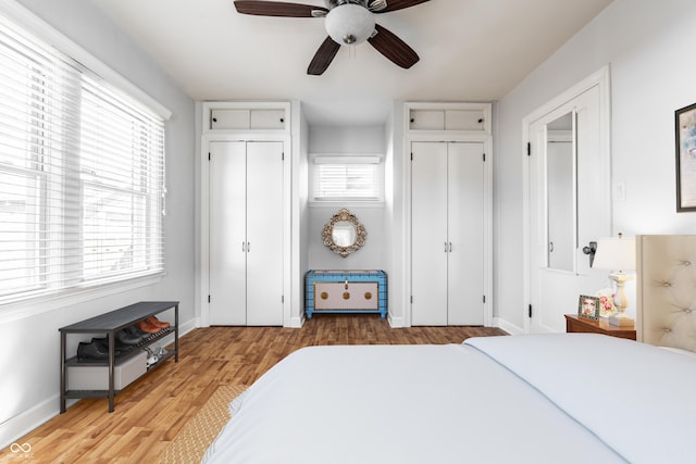 bedroom with ceiling fan, baseboards, two closets, and wood finished floors