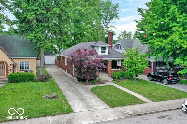 view of front of property featuring a detached garage, a porch, a front yard, a chimney, and an outdoor structure