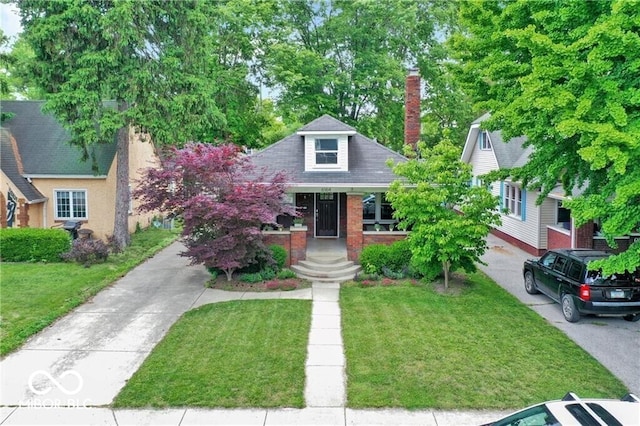 view of front of house featuring brick siding, a chimney, and a front lawn