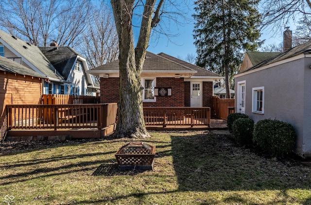 back of house with a wooden deck, fence, brick siding, and an outdoor fire pit