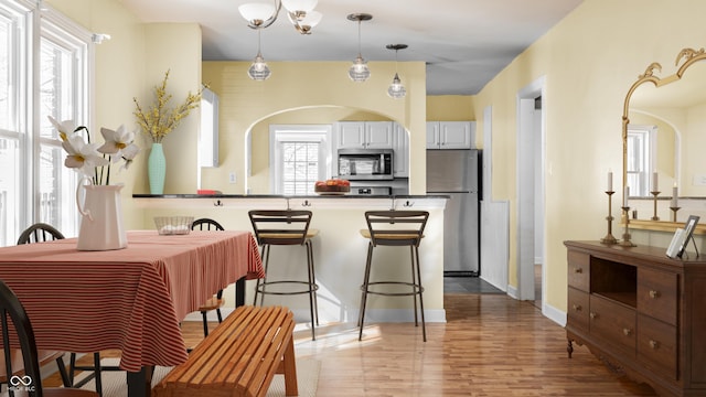 kitchen featuring a peninsula, white cabinets, light wood-style floors, appliances with stainless steel finishes, and dark countertops