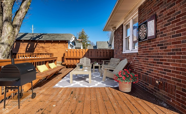 wooden terrace featuring fence and a grill