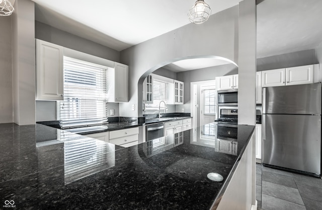 kitchen with arched walkways, white cabinetry, stainless steel appliances, and a sink