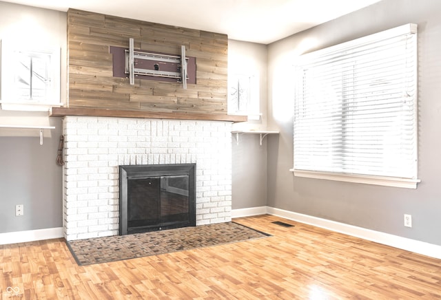 unfurnished living room featuring visible vents, baseboards, wood finished floors, and a fireplace