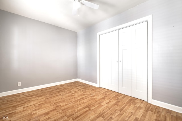 unfurnished bedroom with a closet, light wood-style flooring, a ceiling fan, and baseboards