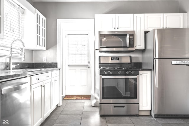 kitchen featuring a sink, appliances with stainless steel finishes, white cabinets, and tile patterned floors