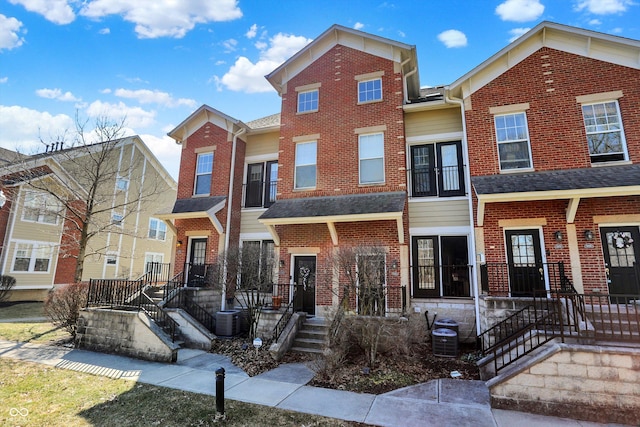 townhome / multi-family property with brick siding and central AC