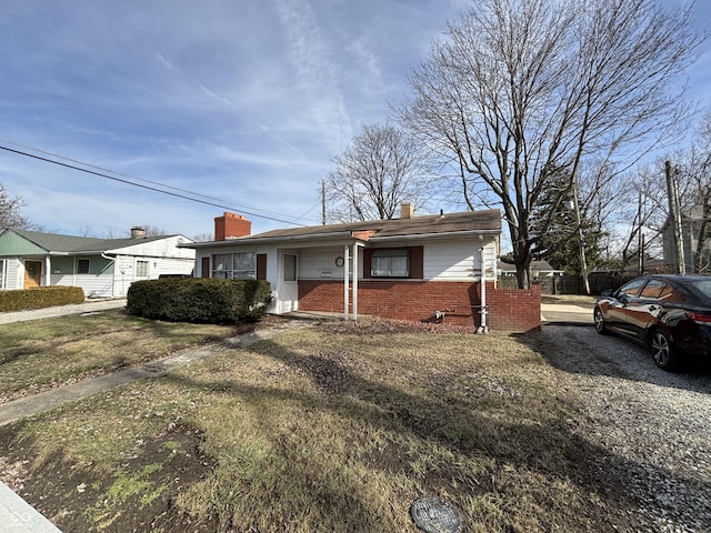 single story home with a front yard, fence, brick siding, and a chimney