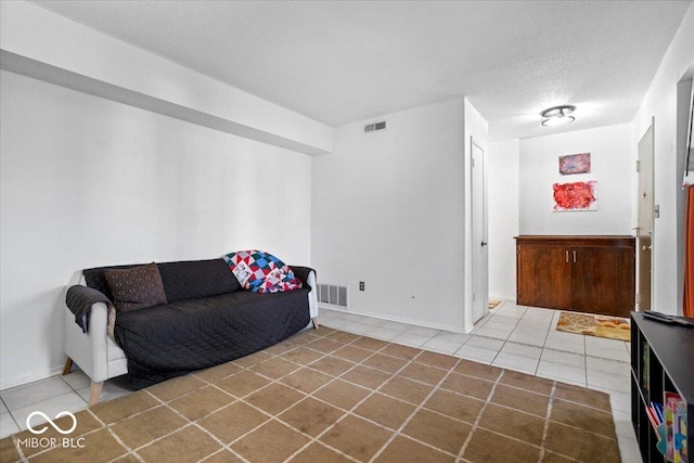 sitting room featuring tile patterned floors, baseboards, visible vents, and a textured ceiling