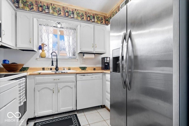 kitchen featuring a sink, dishwasher, stainless steel fridge, white cabinetry, and range