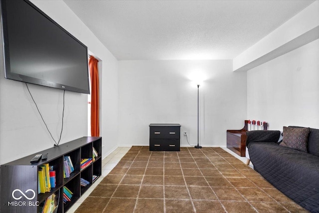 living room with baseboards, a textured ceiling, and dark tile patterned floors