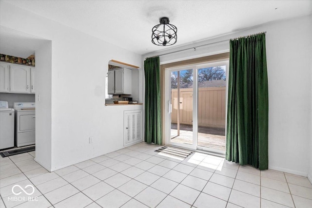 unfurnished dining area with washer and dryer, light tile patterned floors, and a textured ceiling