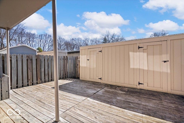 wooden deck featuring an outbuilding, a storage shed, and a fenced backyard