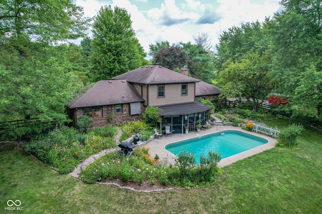 pool featuring a patio area, fence, a yard, and a sunroom