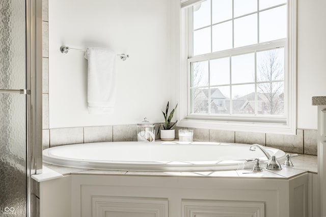 bathroom featuring a garden tub and a shower stall