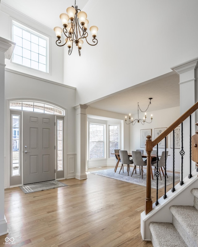 entrance foyer with an inviting chandelier, stairway, light wood-type flooring, and ornate columns