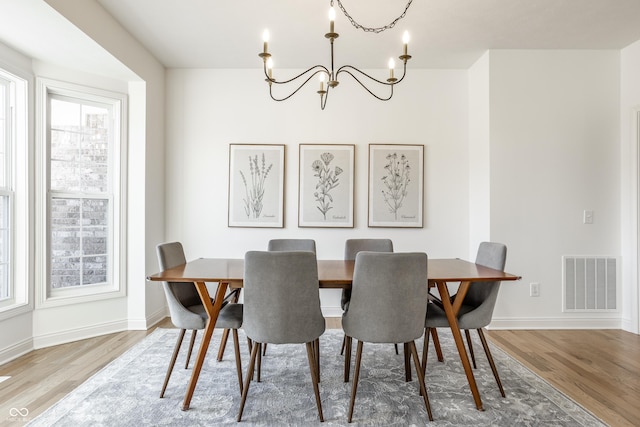 dining area with visible vents, baseboards, an inviting chandelier, and wood finished floors