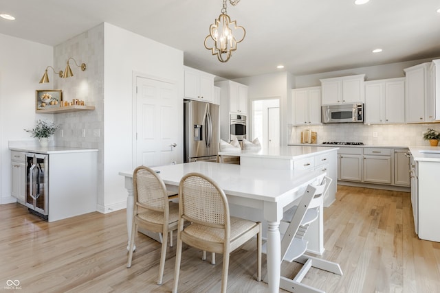 kitchen with a center island, wine cooler, a breakfast bar area, decorative backsplash, and appliances with stainless steel finishes