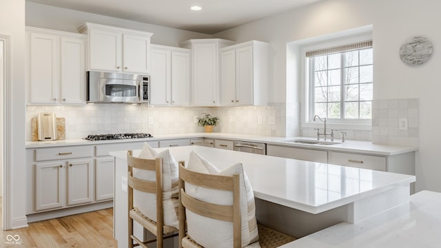 kitchen with a kitchen bar, light wood-style floors, appliances with stainless steel finishes, and a sink