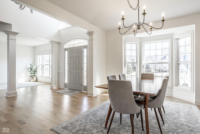 dining area featuring a notable chandelier, wood finished floors, baseboards, and ornate columns