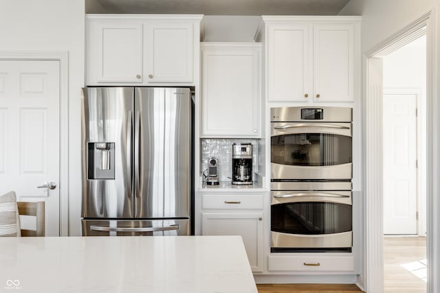 kitchen featuring tasteful backsplash, appliances with stainless steel finishes, and white cabinets