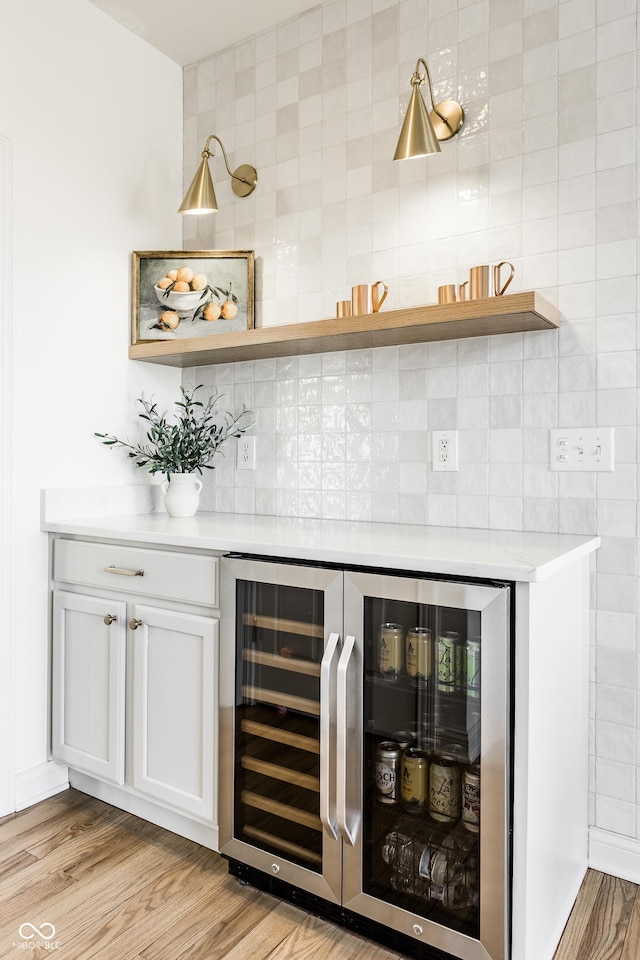 bar featuring a dry bar, wine cooler, light wood-type flooring, and backsplash