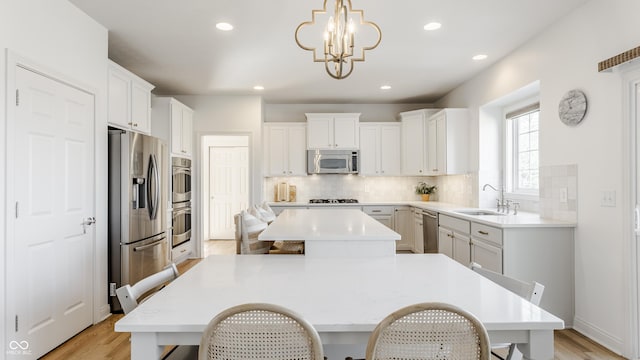 kitchen with a sink, backsplash, a center island, appliances with stainless steel finishes, and light countertops