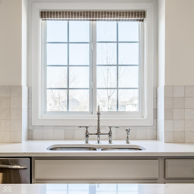 details featuring dishwasher, light countertops, backsplash, and a sink