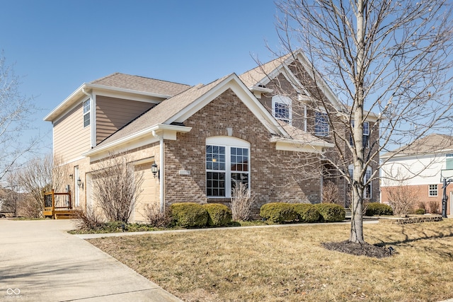 view of front of house with driveway, roof with shingles, a front yard, a garage, and brick siding