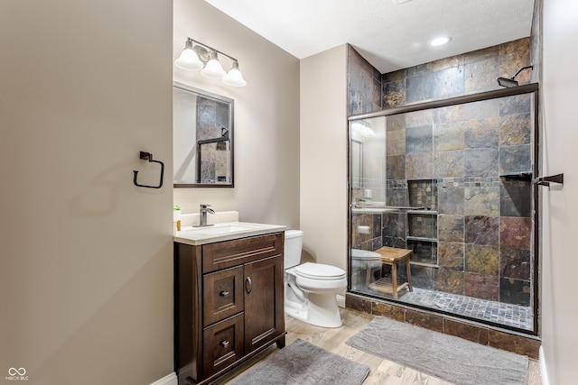 full bathroom featuring vanity, toilet, wood finished floors, and a stall shower