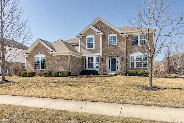 view of front of house featuring a front lawn, brick siding, and a shingled roof