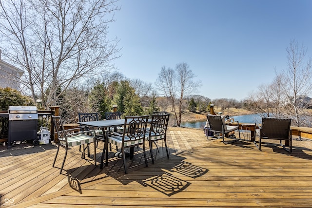 wooden deck featuring outdoor dining space, a water view, and grilling area