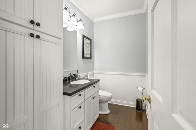 bathroom featuring vanity, wood finished floors, a wainscoted wall, ornamental molding, and toilet