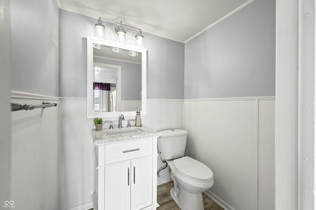 bathroom with a wainscoted wall, toilet, vanity, and wood finished floors