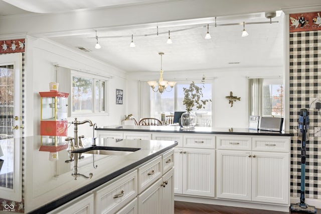 kitchen featuring visible vents, ornamental molding, a notable chandelier, white cabinetry, and a sink